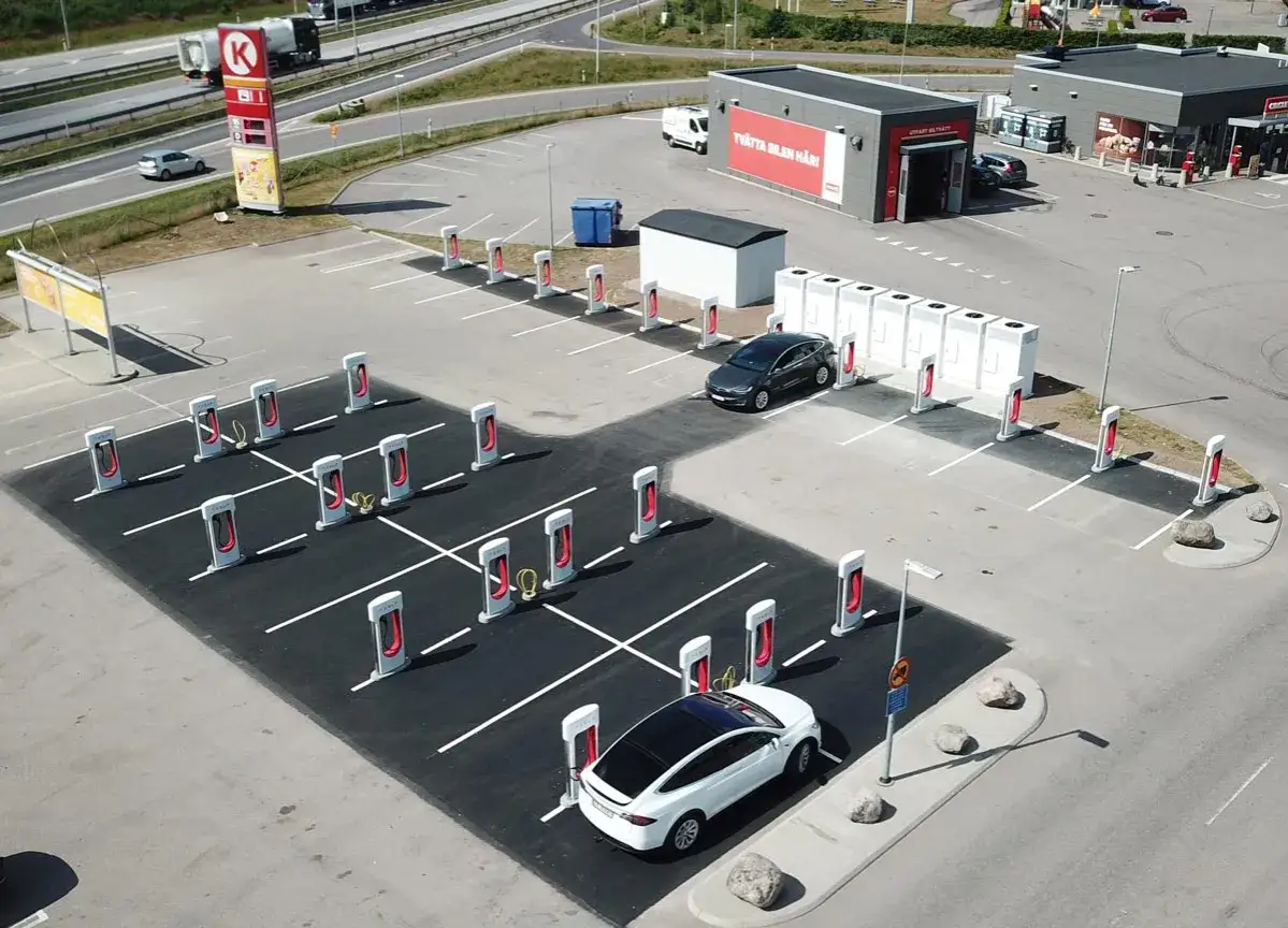 Många Tesla-laddare står redo för elbilarna. En vit Tesla laddar vid en station.