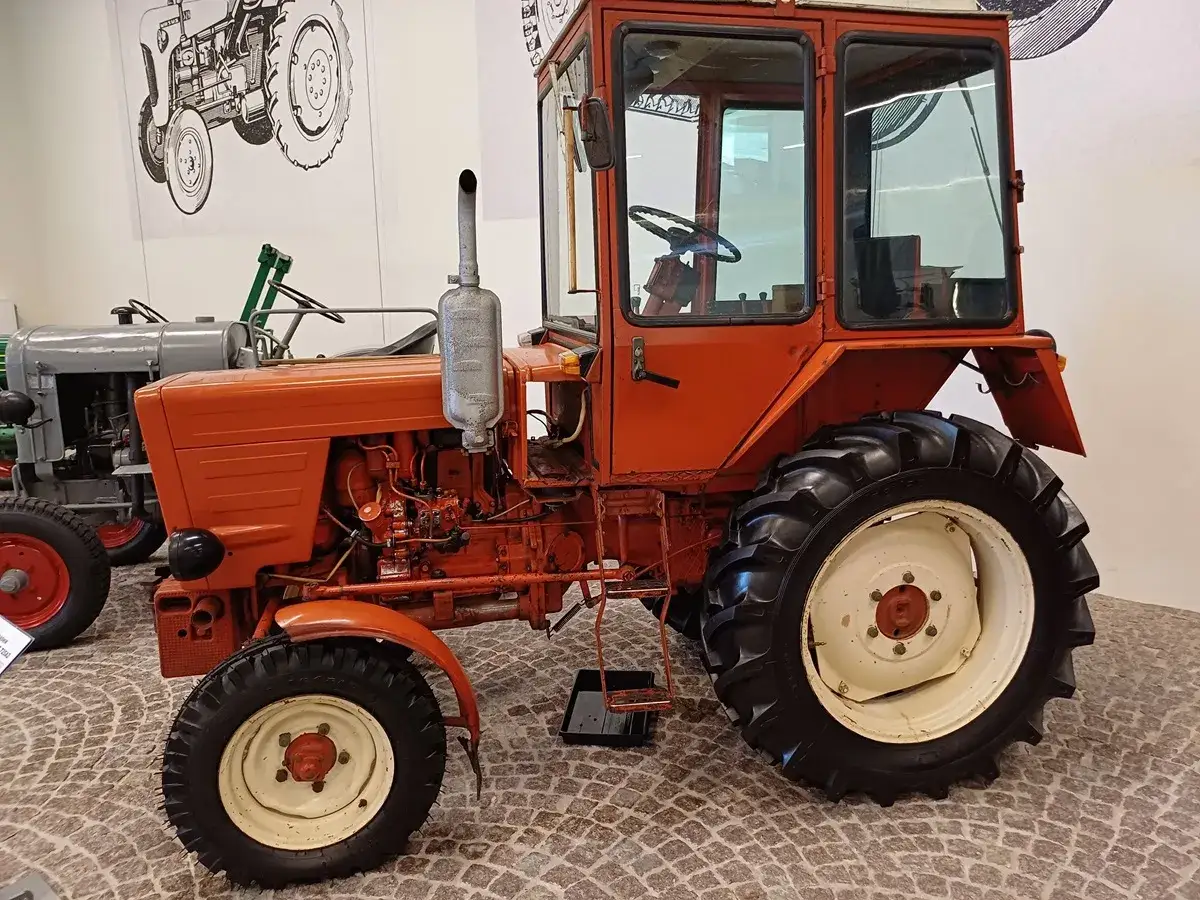 Pomarańczowy, odrestaurowany Władimirec T25 nowy, z kabiną i dużymi kołami, prezentuje się okazale.