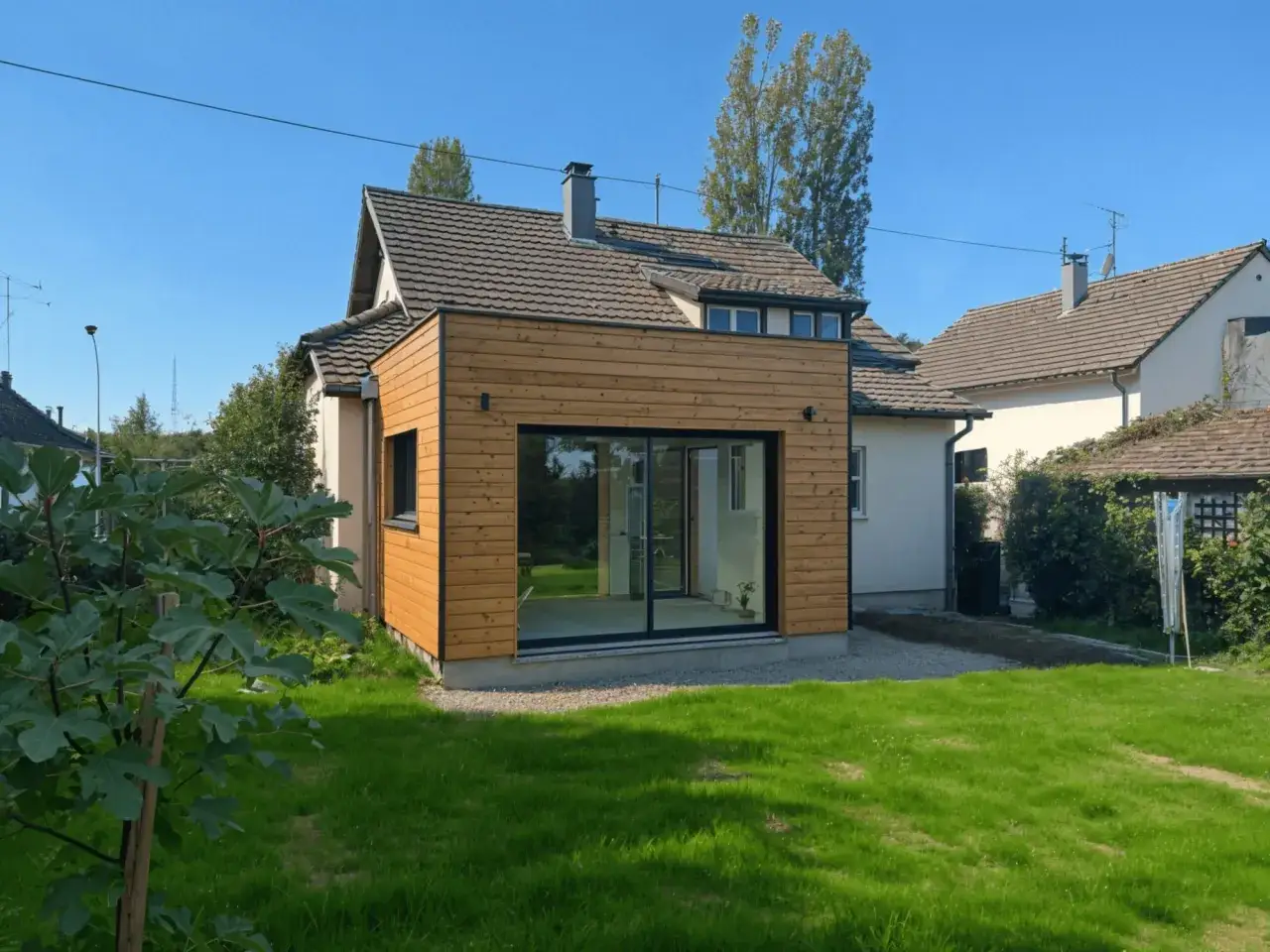 Extension de maison en bois moderne avec grandes baies vitrées, ajoutant de l'espace sans permis de construire.