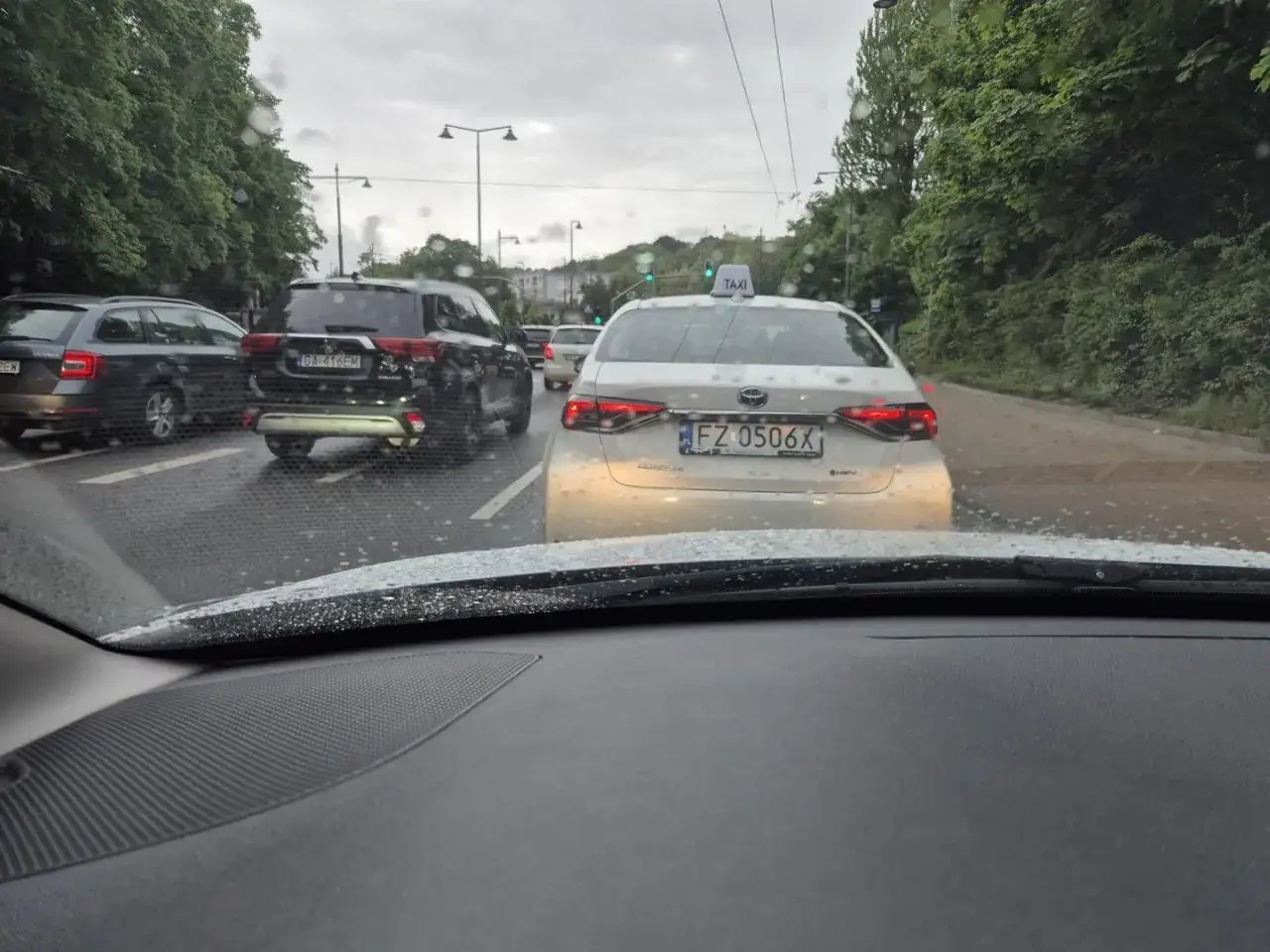 Biała taksówka z tablicą rejestracyjną FZ 0506X w korku.