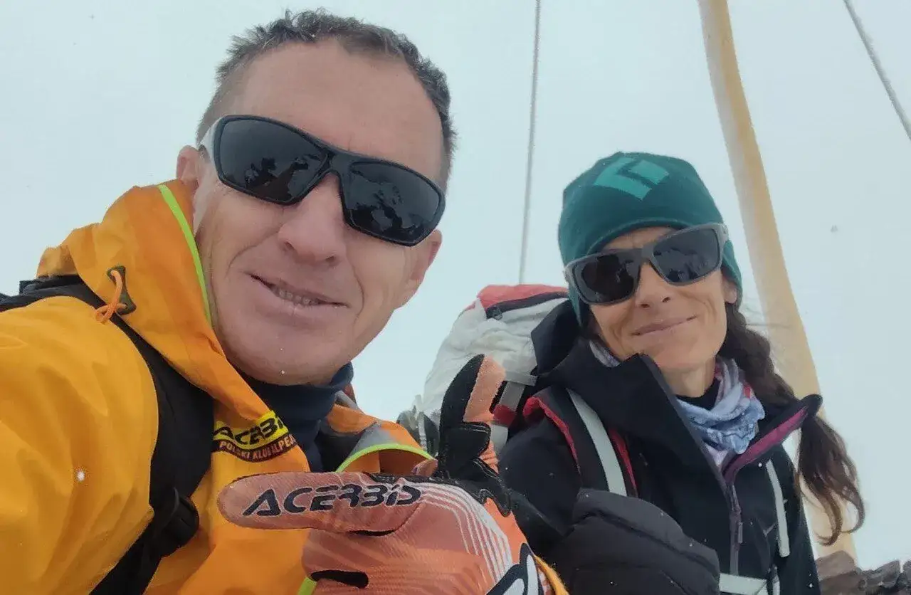 Denis Urubko und Begleiterin auf einem Gipfel, beide mit Sonnenbrillen und warmer Kleidung.