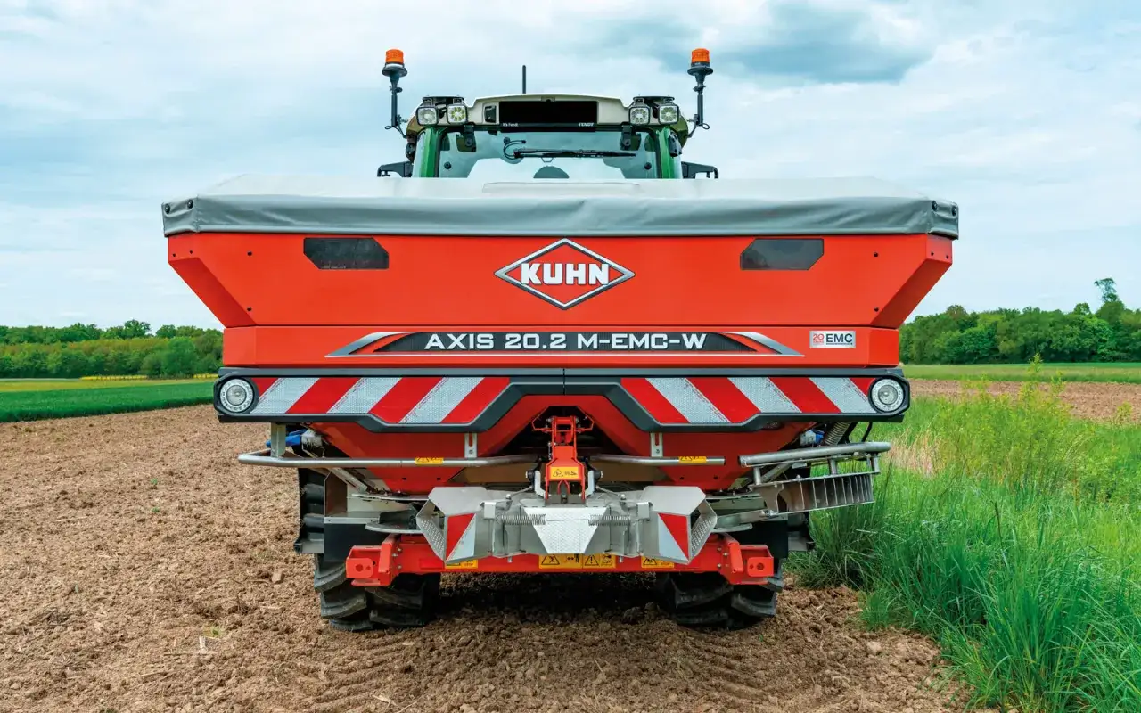 Un épandeur Kuhn AXIS 20.2 M-EMC-W, prêt à distribuer du nexen engrais sur un champ labouré.