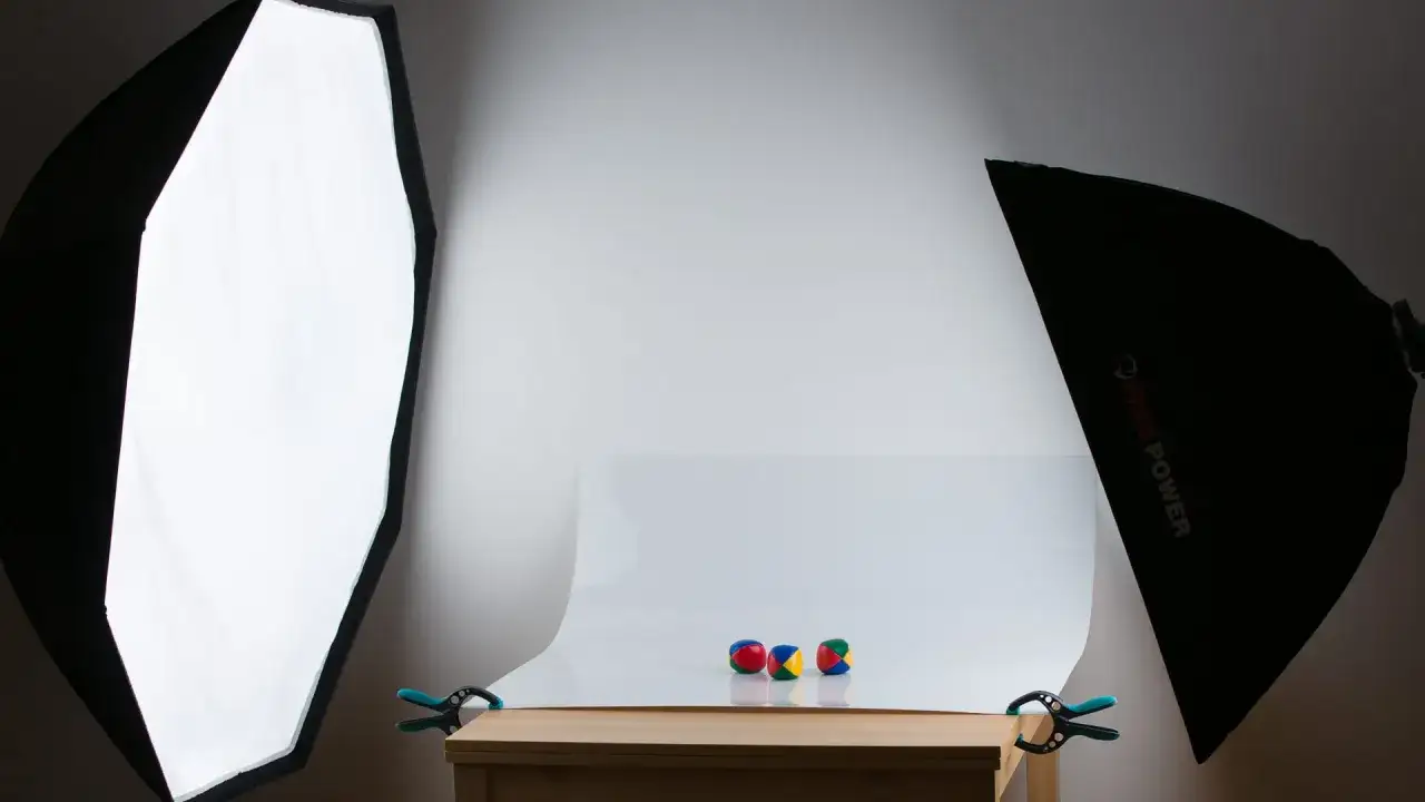 Tres pelotas de malabares de colores sobre una mesa, iluminadas por dos softboxes. Fondo blanco foto.