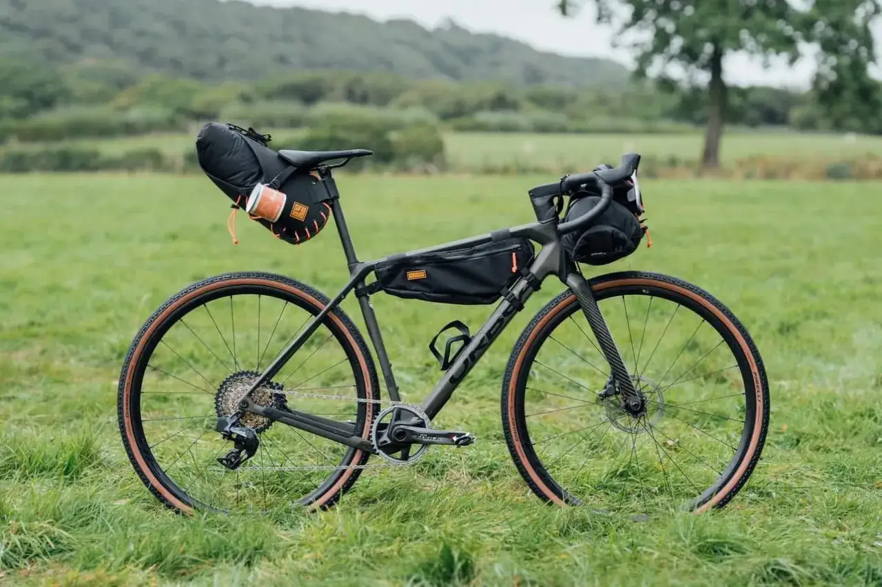 Rower gravelowy gotowy na bikepacking MTB. Torby na ramie, pod siodłem i na kierownicy sugerują daleką podróż.