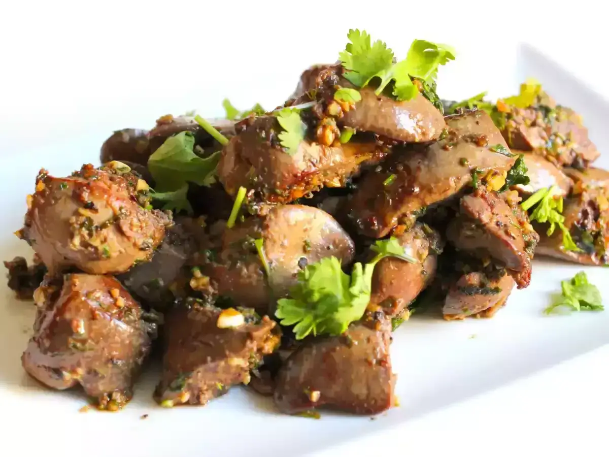 D&eacute;licieux foie de volaille saut&eacute; avec des herbes fra&icirc;ches et de l'ail, servi sur une assiette blanche.