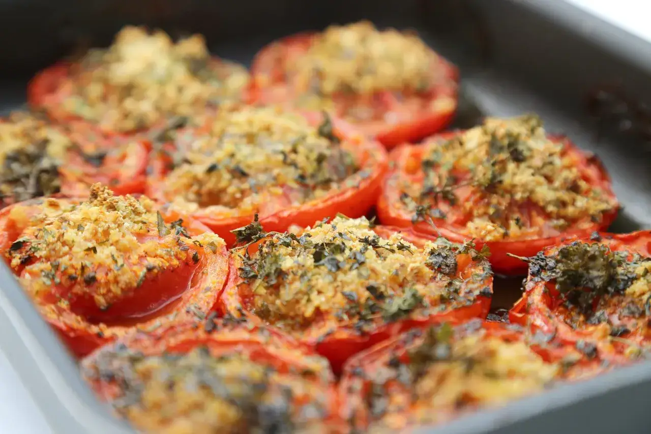 Tomates au four garnies d'une chapelure dorée et d'herbes aromatiques, prêtes à être dégustées.
