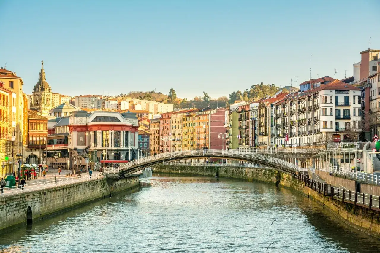 Colorful buildings line a river in Bilbao, Spain, a perfect backdrop for day trips from the city.