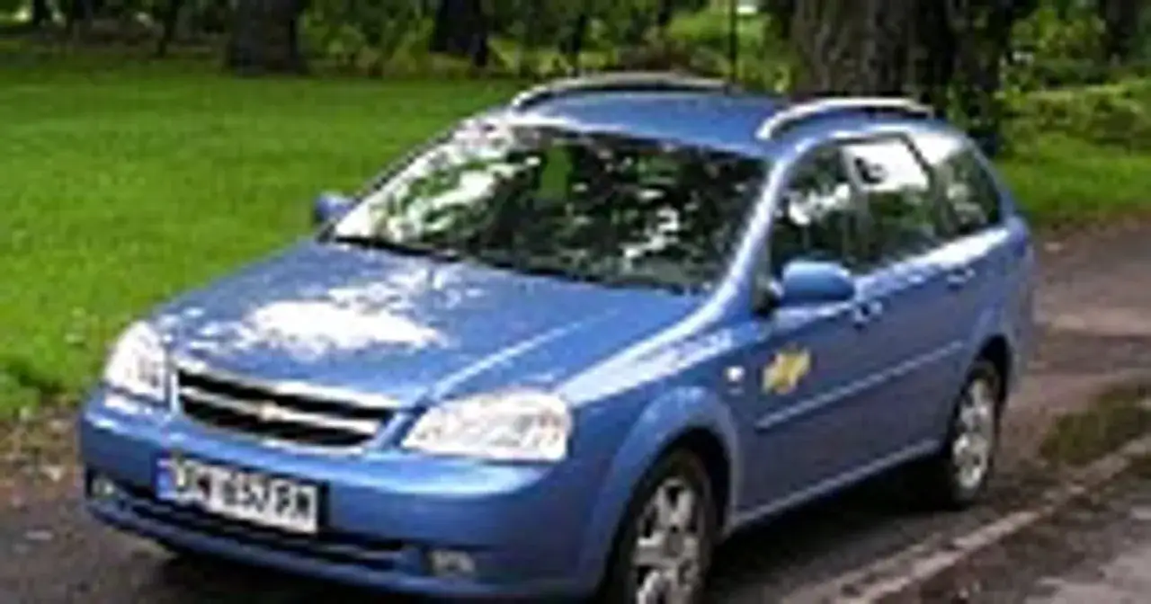 Niebieski Chevrolet Lacetti kombi stoi na tle zieleni.