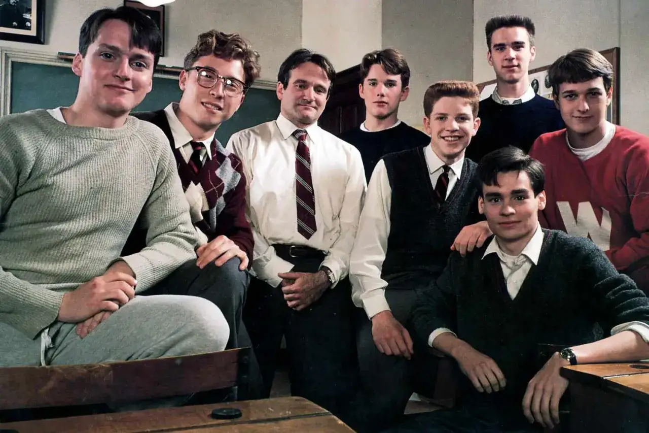 Stowarzyszenie Umarłych Poetów obsada: Robin Williams i młodzi aktorzy w szkolnych strojach.