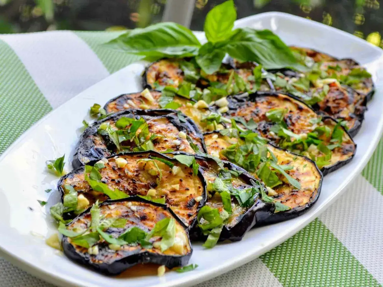 Aubergines confites, une recette italienne savoureuse, garnies de basilic frais et d'ail. Un délice méditerranéen.