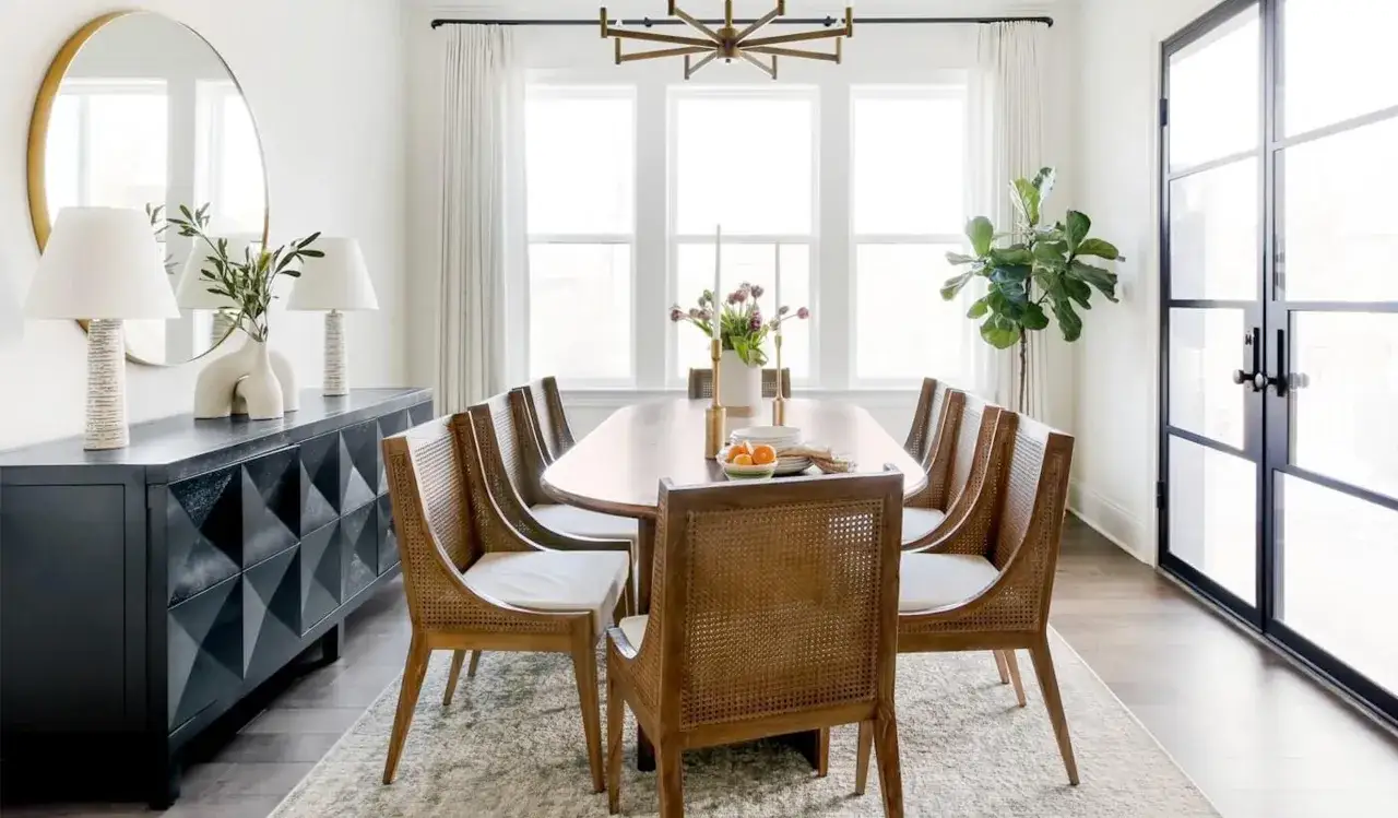Salle à manger moderne avec table ovale et chaises en rotin. La largeur de la table à manger permet d'accueillir confortablement huit personnes.