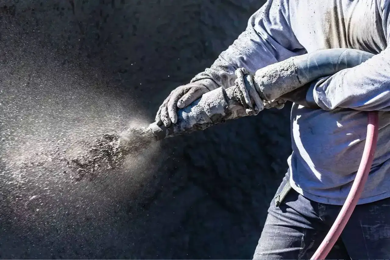 Arbeiter spritzt Beton auf eine Wand. So kann man spritzbeton selber machen.