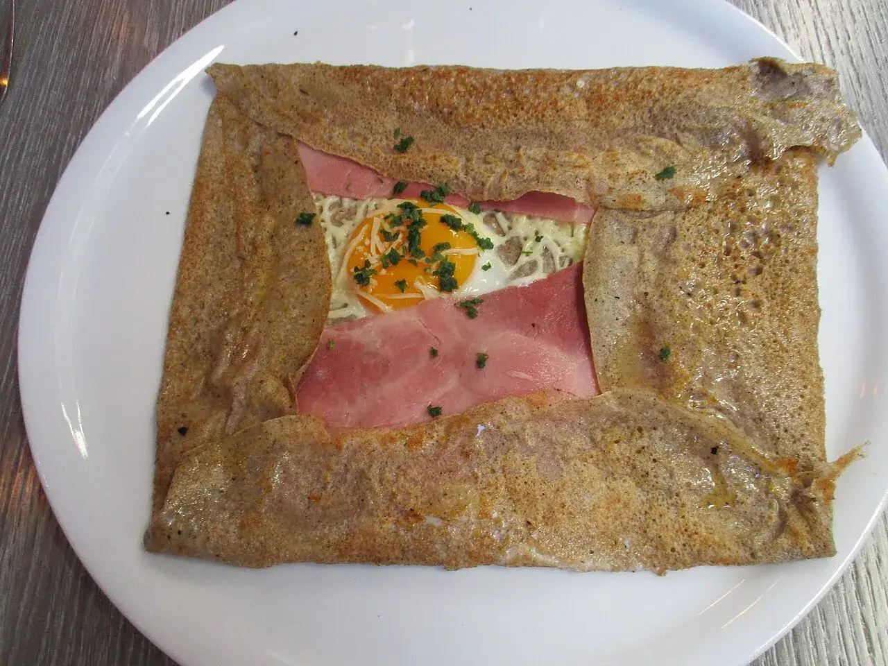 Galette complète, une spécialité culinaire bretonne, garnie de jambon, fromage et œuf.