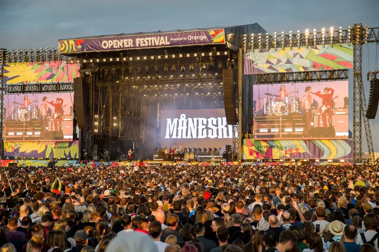 Tłum fanów na koncercie Måneskin podczas Open'er Festival. Na scenie zespół, a na telebimach ich występ.