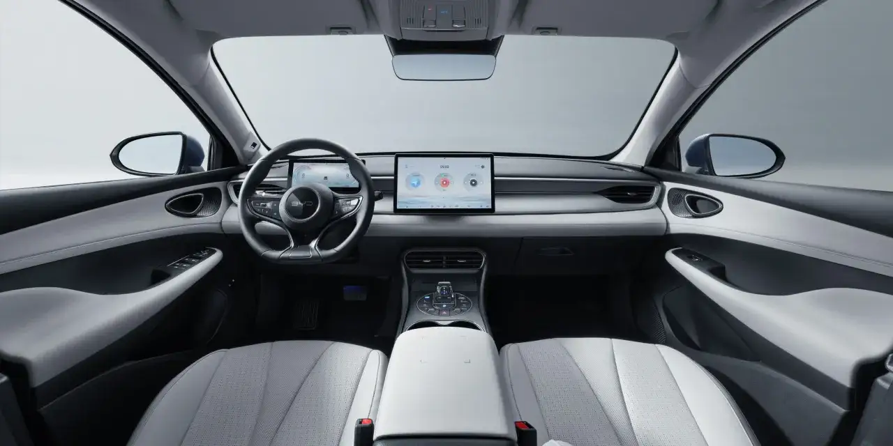 Wnętrze BYD Seal 5: nowoczesna deska rozdzielcza z dużym ekranem dotykowym, cyfrowymi zegarami i eleganckimi, dwukolorowymi fotelami.