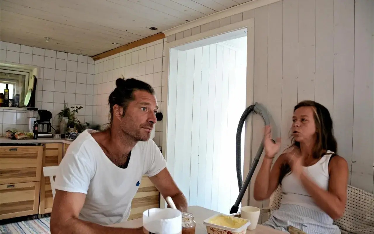 Markus Torgeby med familj vid köksbordet. En man med håret uppsatt i en knut och en kvinna sitter och pratar.