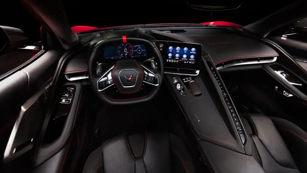 Wnętrze chevrolet corvette c8: cyfrowy kokpit, ekran multimediów i sportowe fotele z czerwoną nicią.