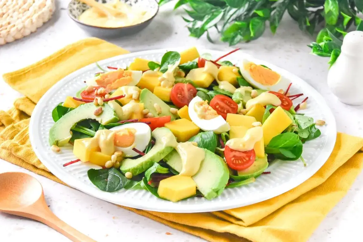 Ensalada de mango con aguacate, huevo duro, tomates cherry y piñones, aderezada con una cremosa salsa.