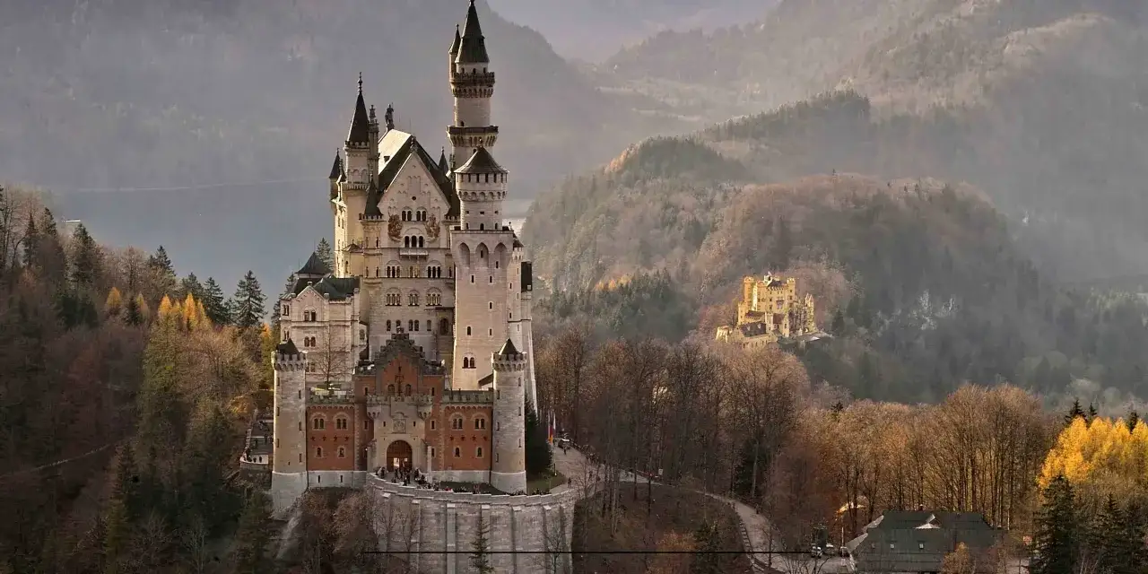 Zamek Neuschwanstein, symbol tego, z czego słyną Niemcy, w otoczeniu jesiennych lasów.