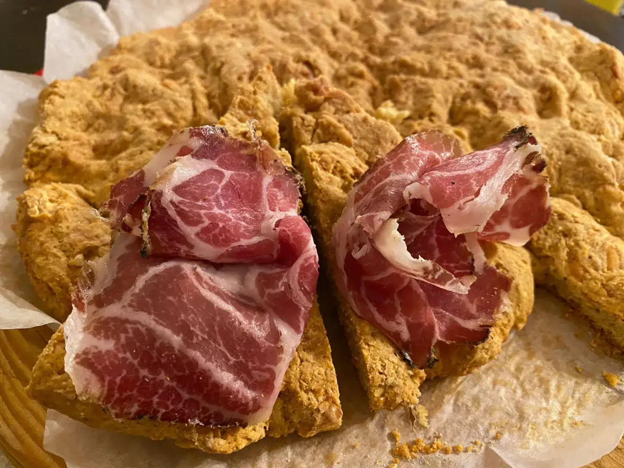 La ciaccia di Pasqua toscana, fragrante e dorata, è guarnita con fette di salume rosato.