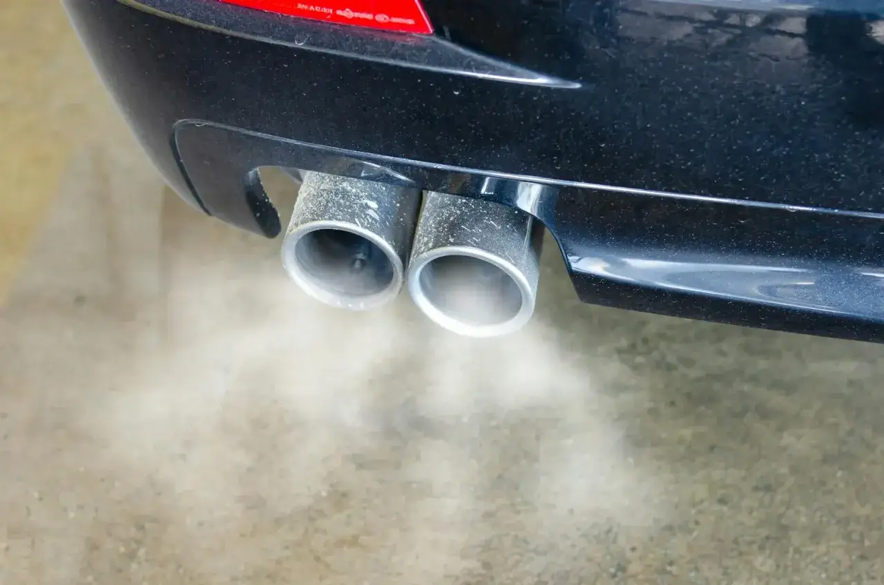 Dym z podwójnej końcówki wydechu samochodu, objawy złej jakości paliwa diesel.