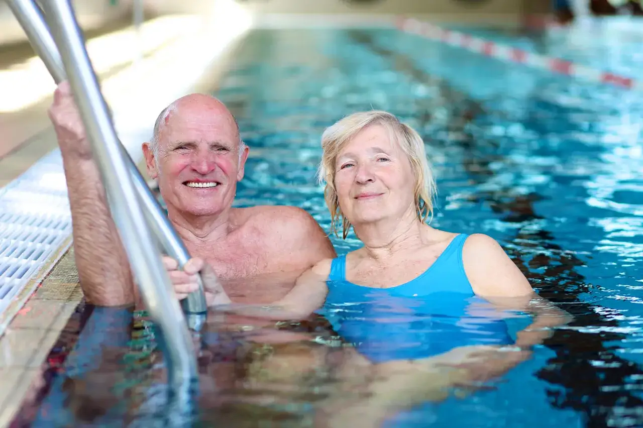 Smiling couple enjoying adult swim lessons in a pool.