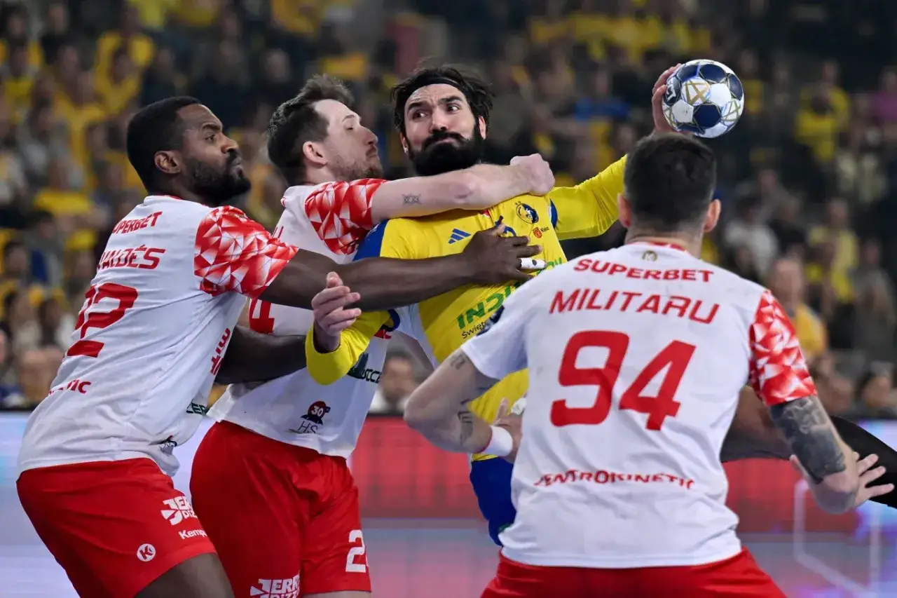 Zacięta walka na boisku podczas meczu Vive. Zawodnicy w białych strojach próbują zatrzymać gracza w żółtej koszulce z piłką.