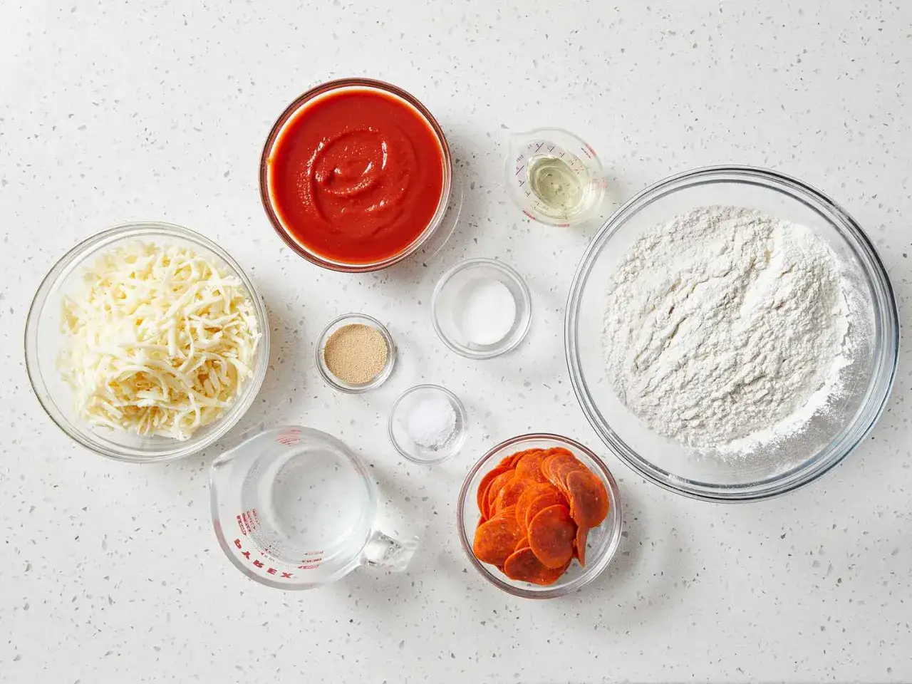 Alle Zutaten f&uuml;r Pizzateig: Mehl, Wasser, Hefe, Salz, &Ouml;l, K&auml;se und Pepperoni.