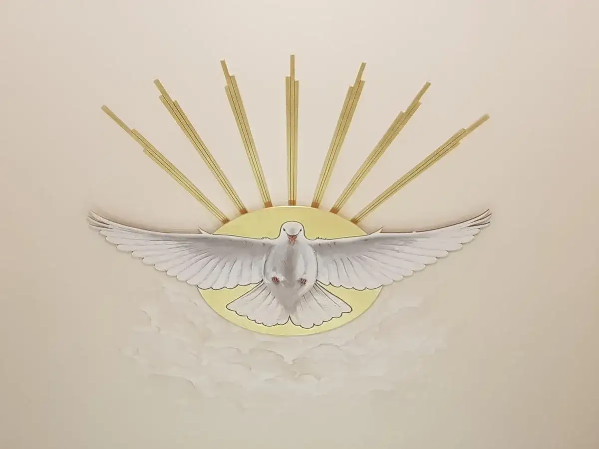 Biały gołąb z rozpostartymi skrzydłami, otoczony złotymi promieniami i chmurami, to piękne symbole Ducha Świętego.