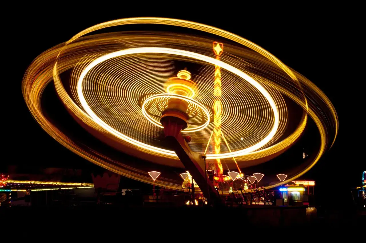 Luci dorate creano spirali ipnotiche, mostrando come fare foto in movimento di un'attrazione da luna park in piena azione.