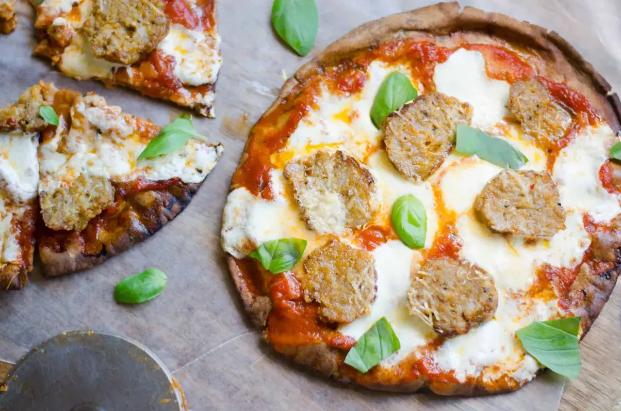 Pyszna pizza z kawałkami kiełbaski i roztopionym serem. Idealny wybór, jeśli zastanawiasz się, jaki ser do pizzy wybrać.