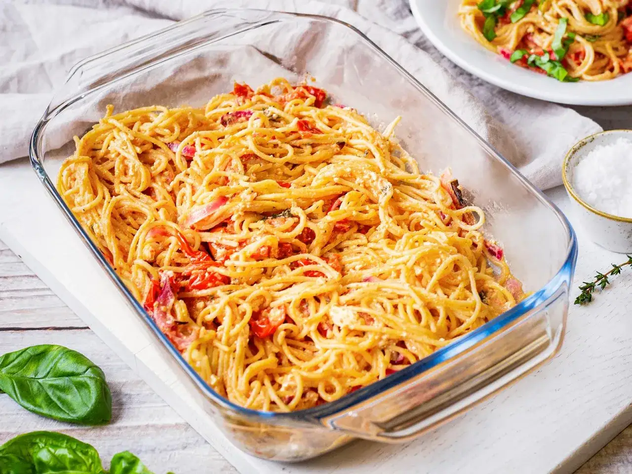 Fertige One Pot Pasta im Ofen, cremige Spaghetti mit Tomaten und Kräutern in einer Auflaufform.