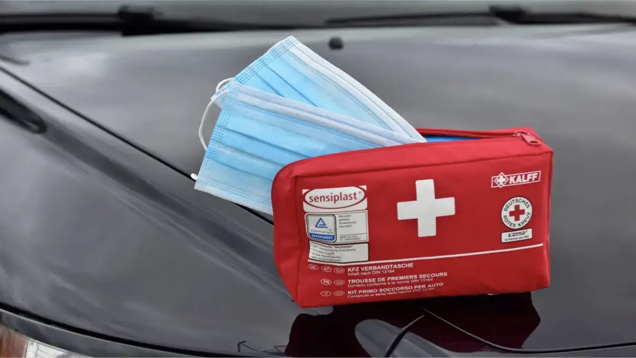 Roter Verbandskasten mit Masken auf einem Auto. Der Verbandskasten ist abgelaufen, aber die Masken sind neu.