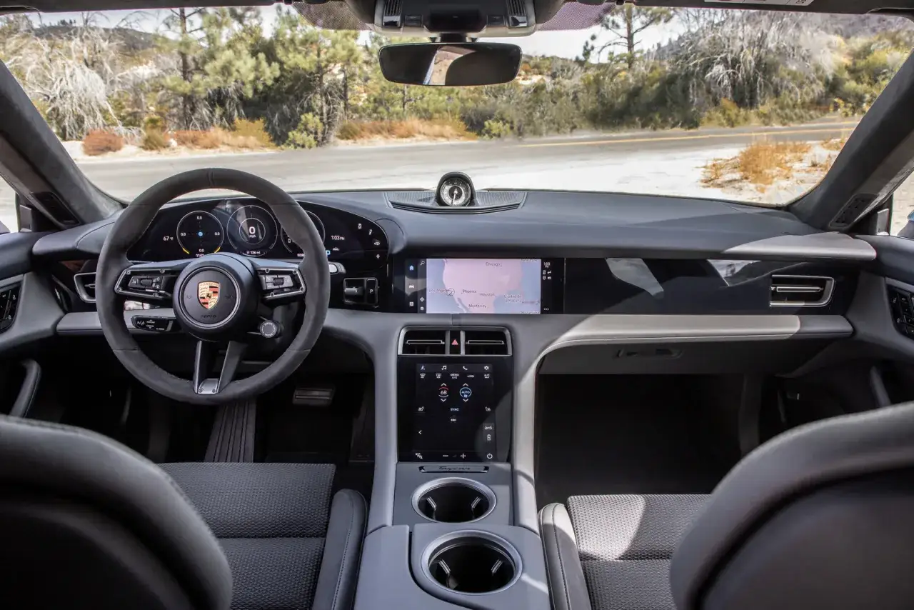Wnętrze Porsche Taycan Turbo S z cyfrowymi zegarami, ekranem nawigacji i sportową kierownicą.