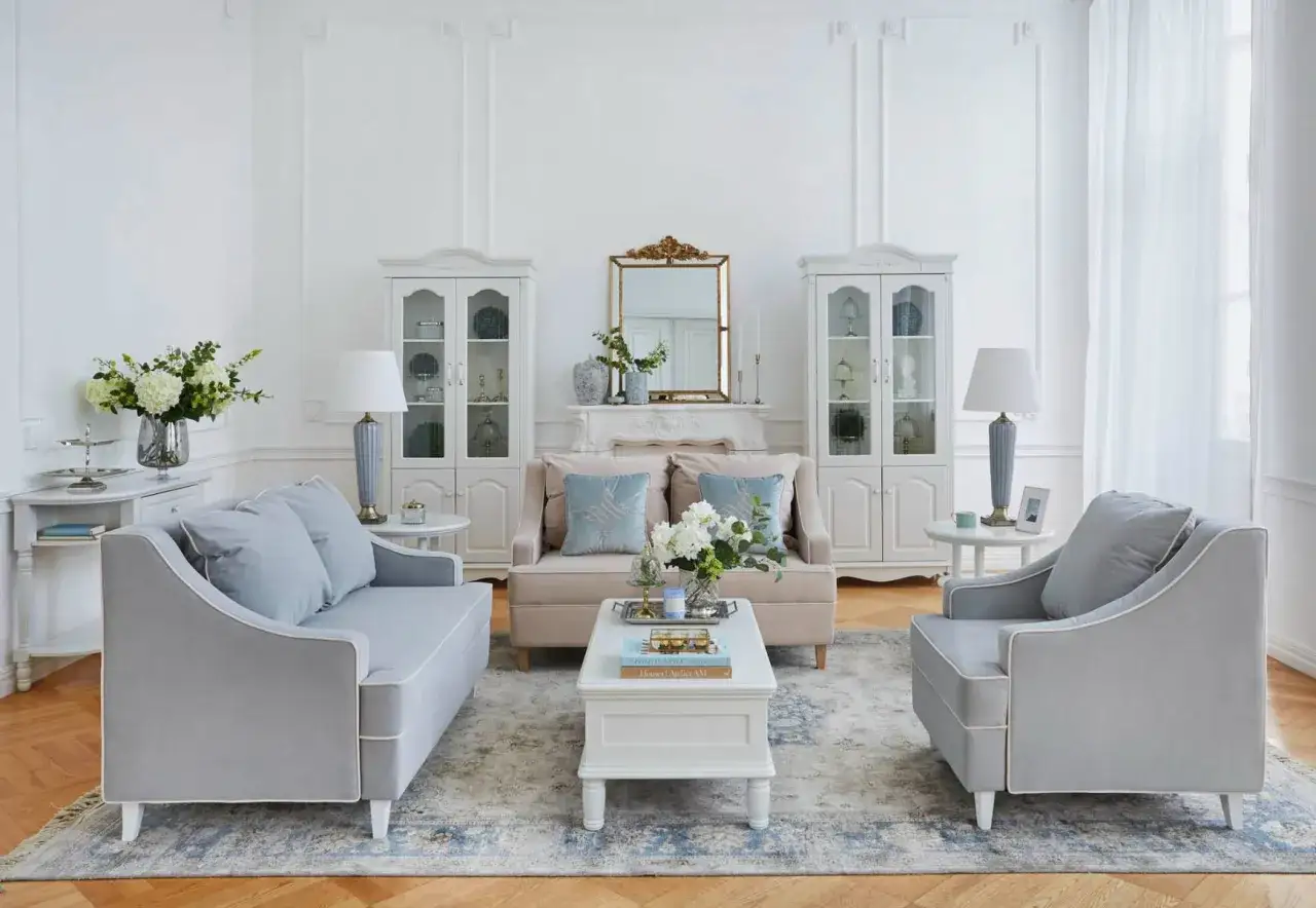 Salotto in stile shabby chic moderno con divani grigi, poltrone, tavolino bianco, specchio dorato e vetrine.