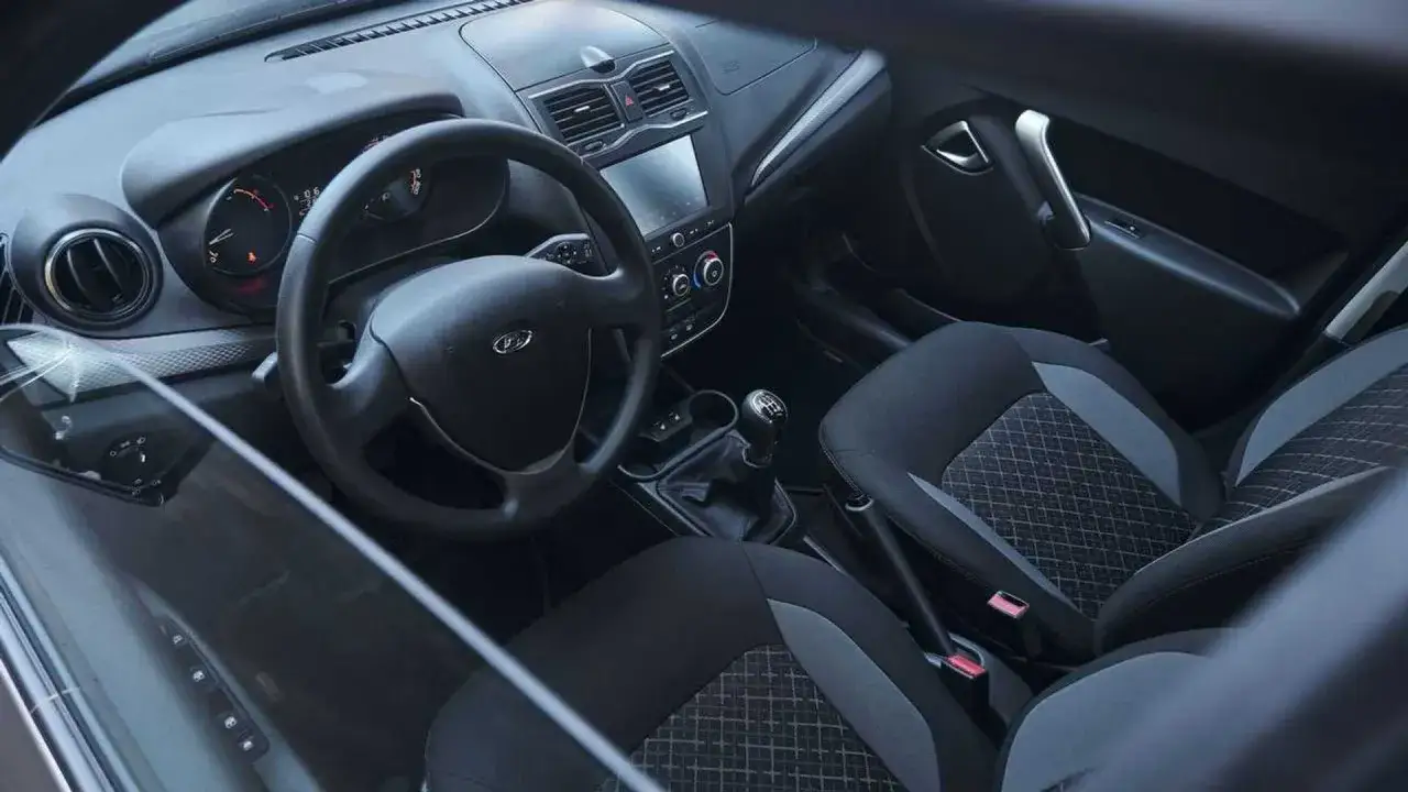 Interior de un Lada Granta con asientos de tela, volante y palanca de cambios.