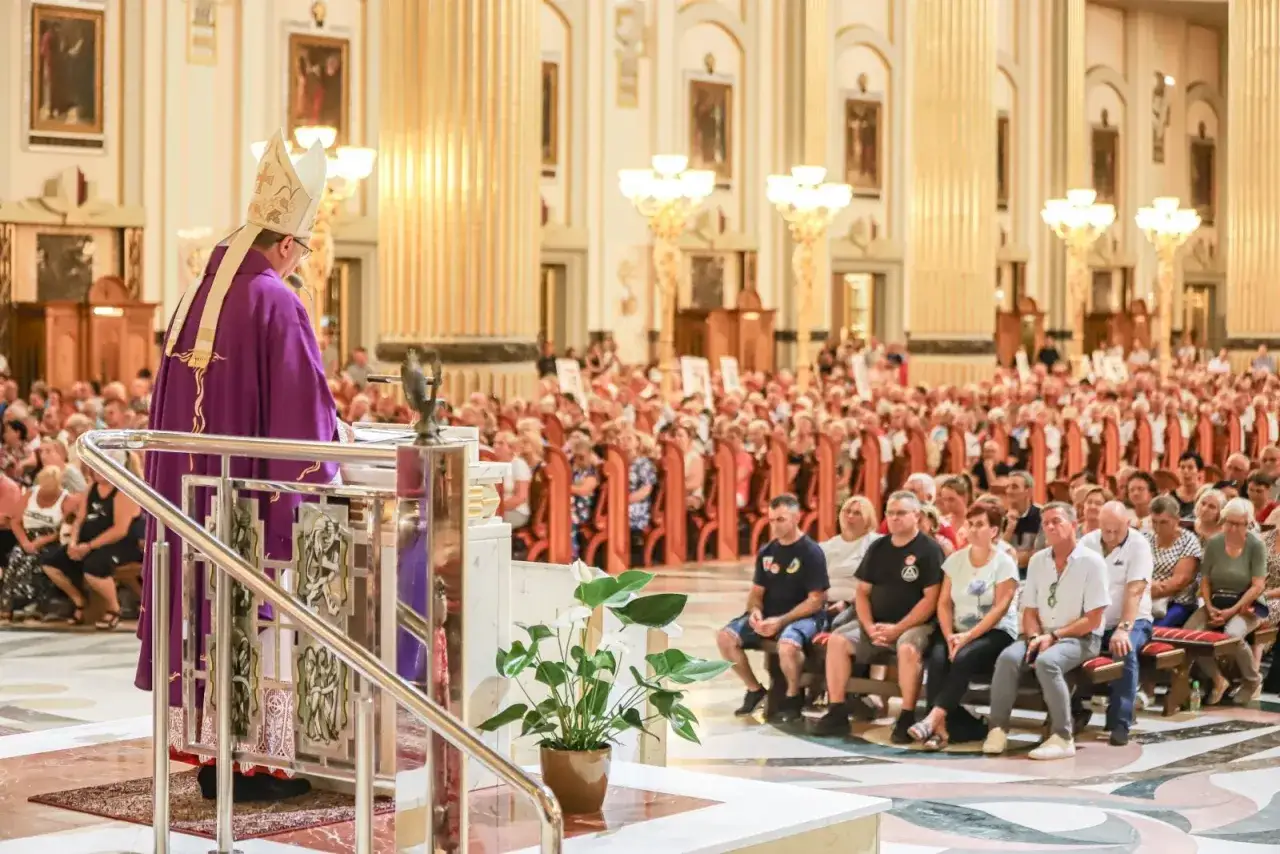 Biskup w purpurowej szacie przemawia do wiernych. Dyskusja o przyczynach zmian w tekstach modlitw w nowym mszale rzymskim.