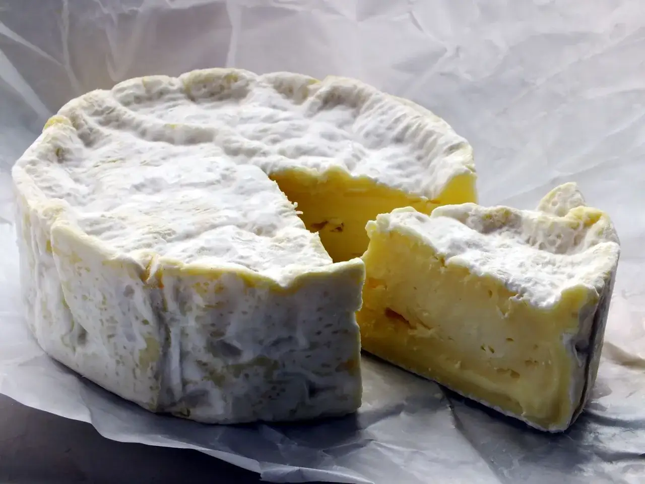 Queso cremoso con corteza blanca, un trozo cortado revela su interior amarillo. Una imagen que ayuda a entender la diferencia entre camembert y brie.