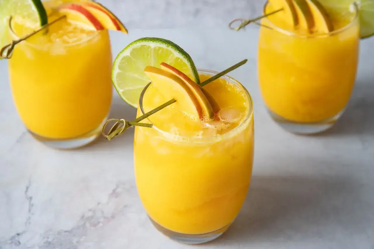 Orzeźwiający drink z mango, udekorowany plasterkiem limonki i owocu. Idealny na upalne dni.