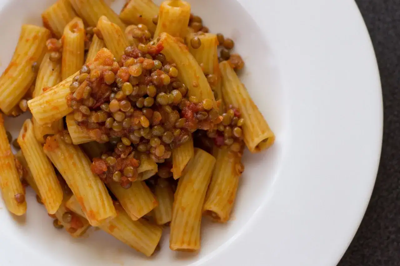 Piatto di rigatoni conditi con un saporito ragù di lenticchie, un classico della cucina italiana.