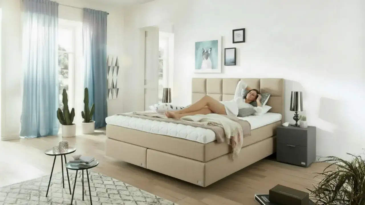 Frau liegt auf einem Boxspringbett, das zu hart ist. Sie streckt sich und schaut zur Decke.