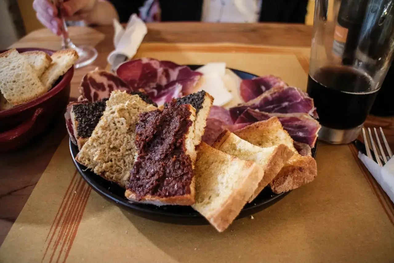 Tagliere con salumi e formaggi, pane tostato con paté di olive e pomodoro, un assaggio dei piatti tipici umbria.