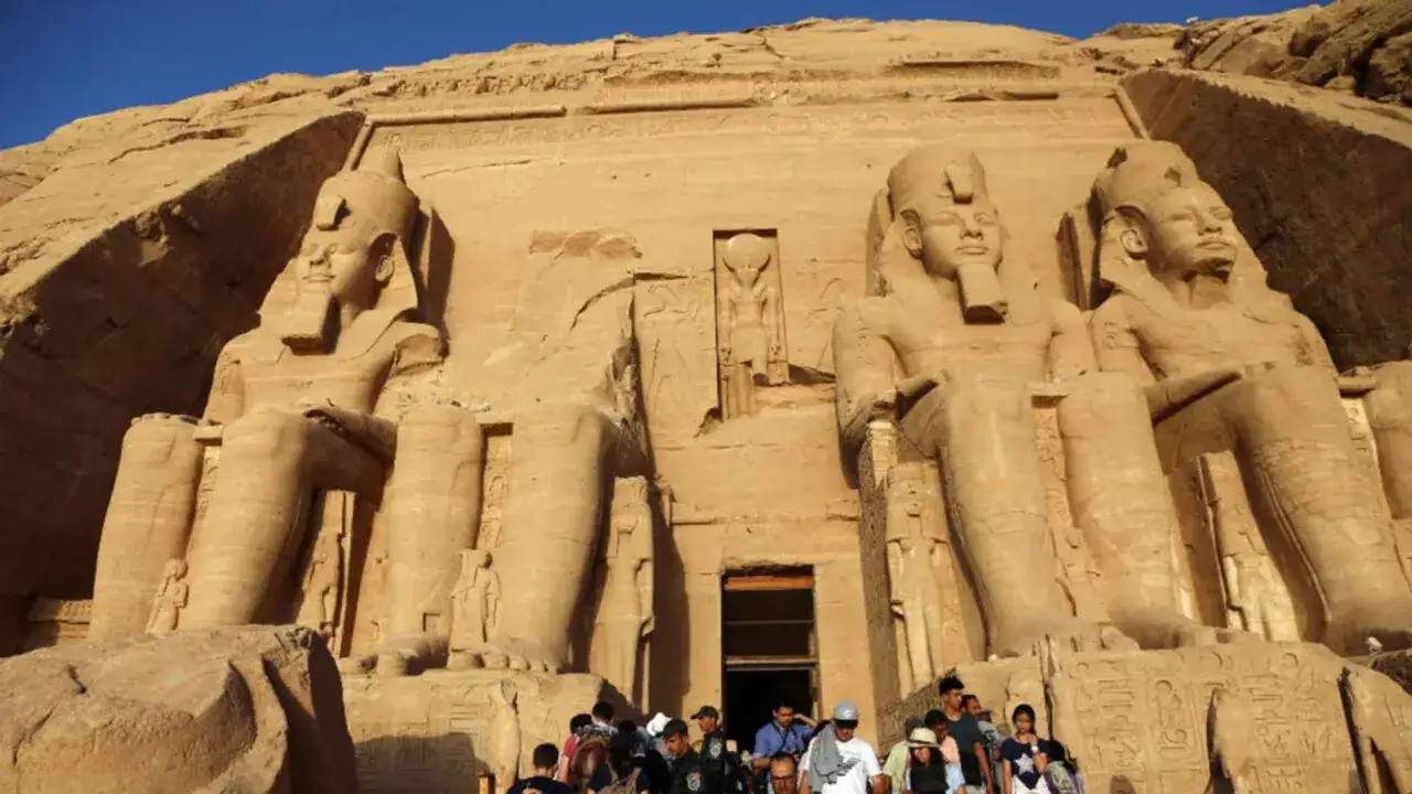 Gigantescas estatuas de Ramsés II flanquean la entrada al templo de Abu Simbel. Turistas admiran la magnificencia de esta obra milenaria.