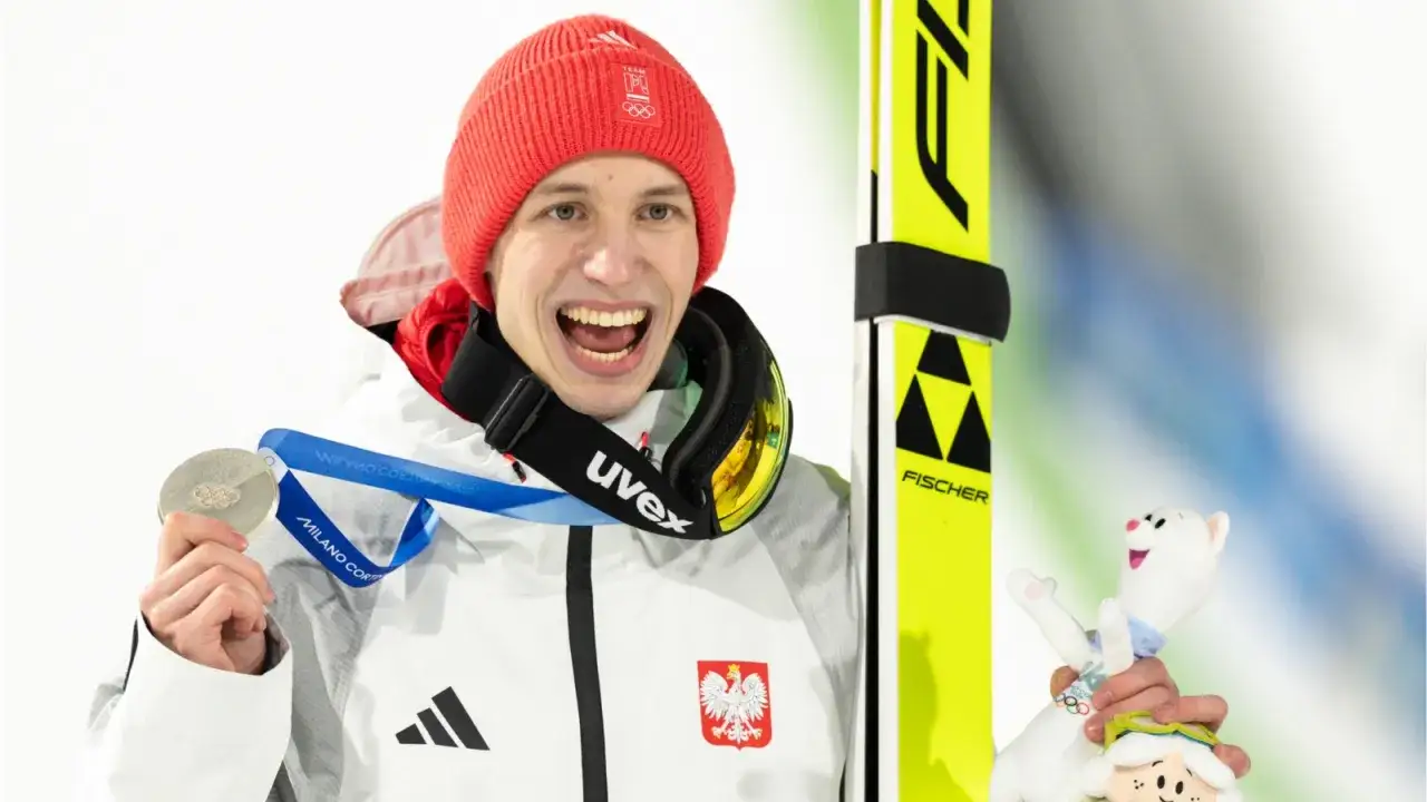 Szczęśliwy skoczek narciarski z medalem olimpijskim i maskotką. Ciekawe, ile wynosi emerytura olimpijska dla takich sportowców.