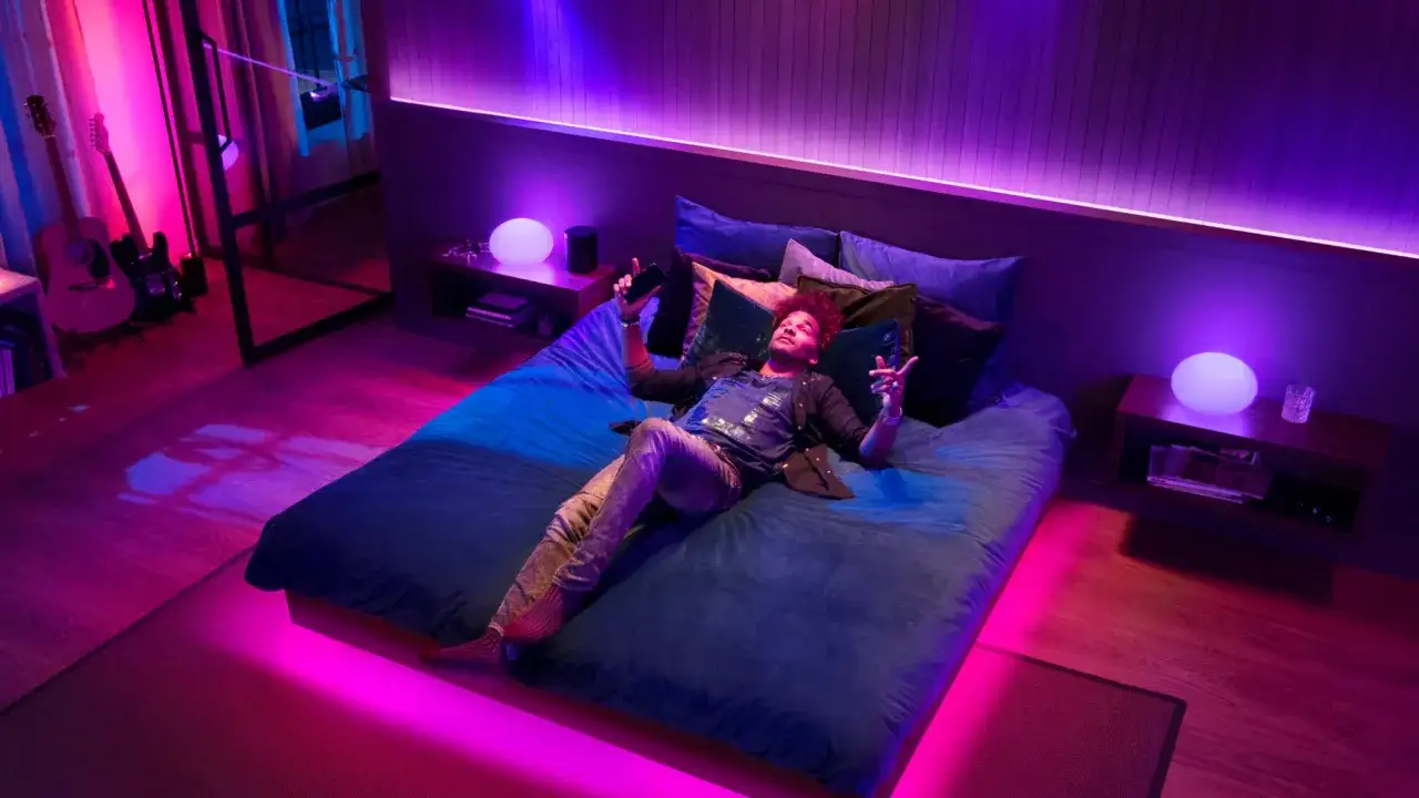 Mann liegt auf Bett, umgeben von Philips Hue Licht, das zur Spotify-Musik synchronisiert ist. Gitarren im Hintergrund.