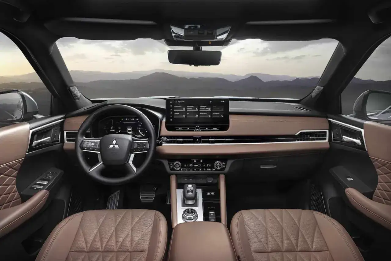 Wnętrze Mitsubishi Outlander z brązową skórzaną tapicerką i nowoczesnym panelem. Wiele osób szuka Mitsubishi Outlander opinie, by poznać ten samochód.