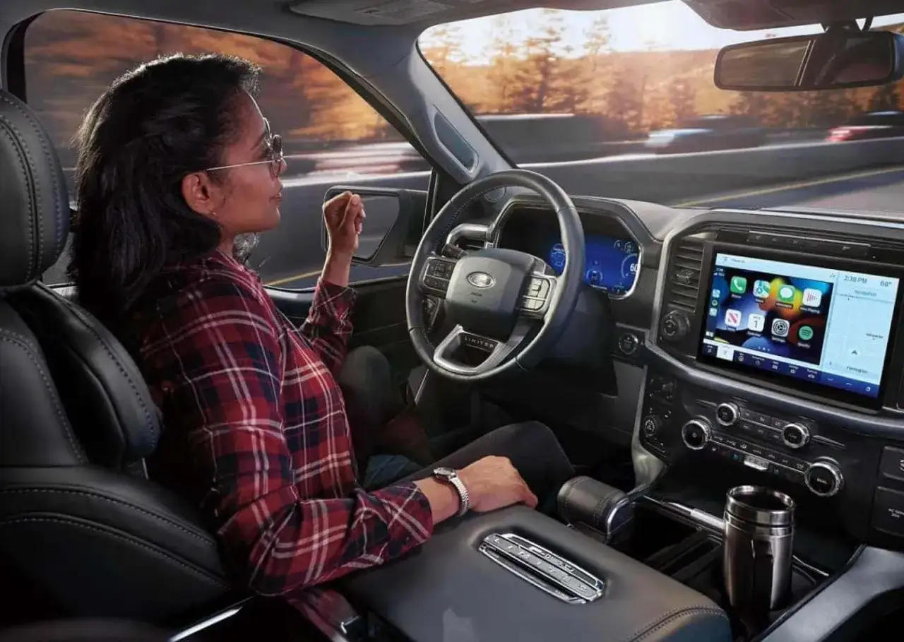 Int&eacute;rieur d'un camion Ford, une femme au volant profite du paysage.