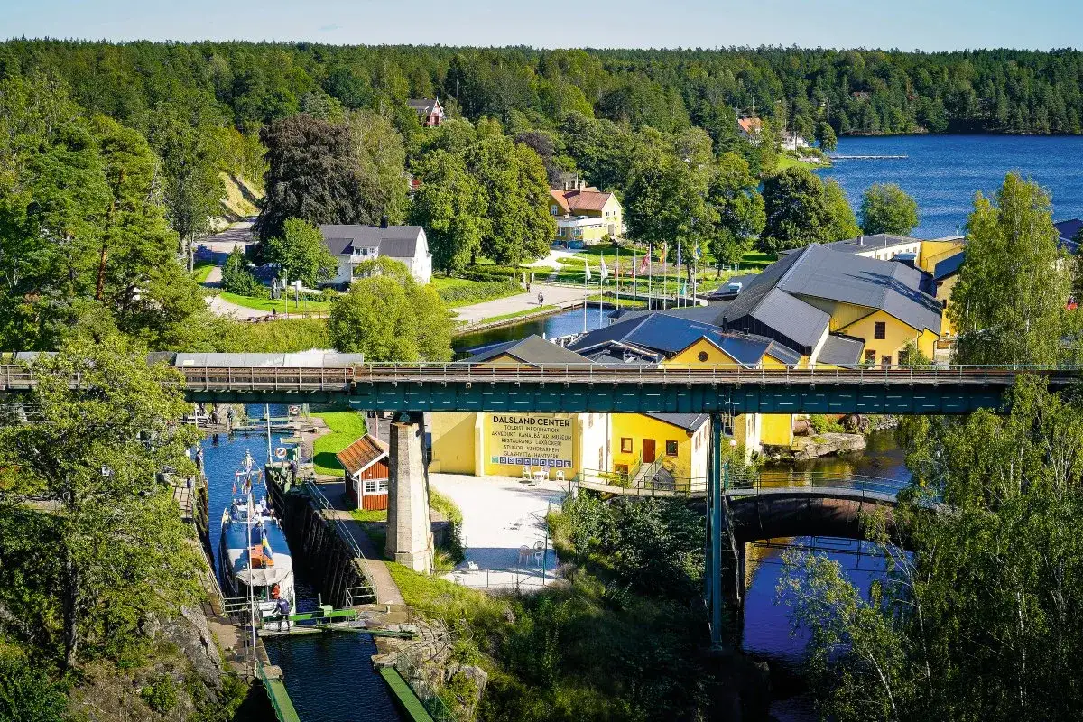 Dalsland Center mit gelben Gebäuden und einem Kanal, wo ein Boot durchfährt. Hier kann man auch Kanu fahren.