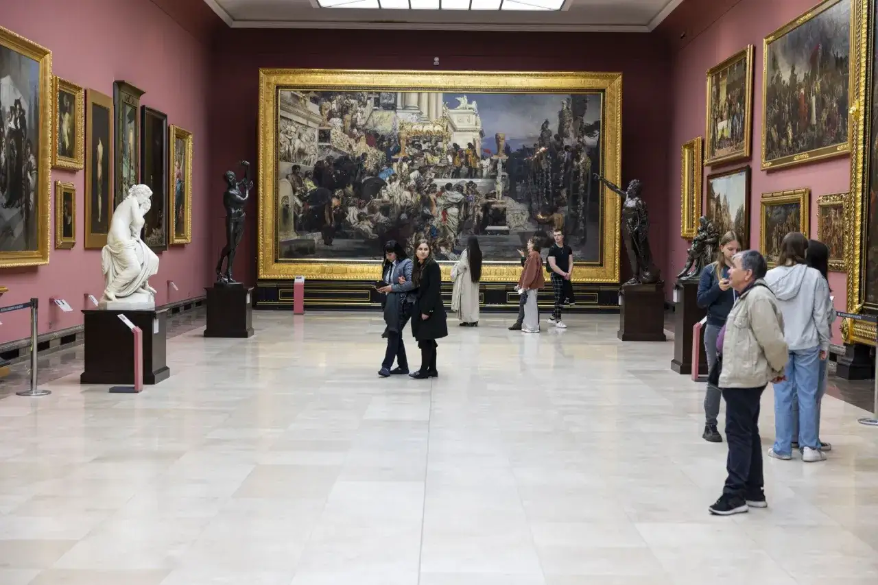 Wielka sala muzealna z obrazami i rzeźbami. Grupa zwiedzających podziwia dzieła sztuki, ciesząc się okazją do zakupu **biletów za złotówkę**.