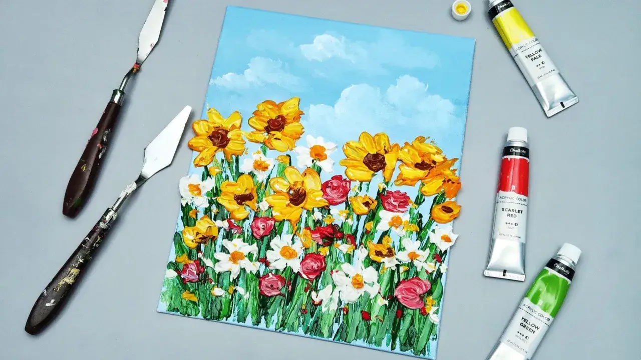 Tableau de fleurs en acrylique avant ou après peinture, avec des tubes de peinture jaune, rouge et verte, et des couteaux à peindre.